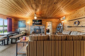Indbydende interiør i en hytte med træloft, pejs, sofa, spisebord og et skilt for SkyRun Vacation Rentals.