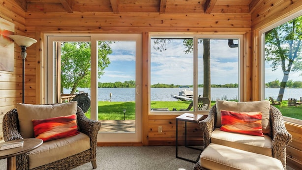 A cozy room with wicker furniture, a small table, and a view of a lake. - Granite Lake Retreat w/ Private Dock (Annandale)