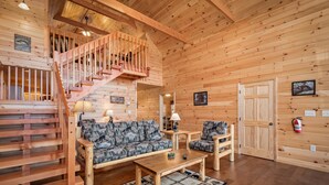 Un interior de madera con una escalera, un sofá, una mesa de centro y una chimenea.