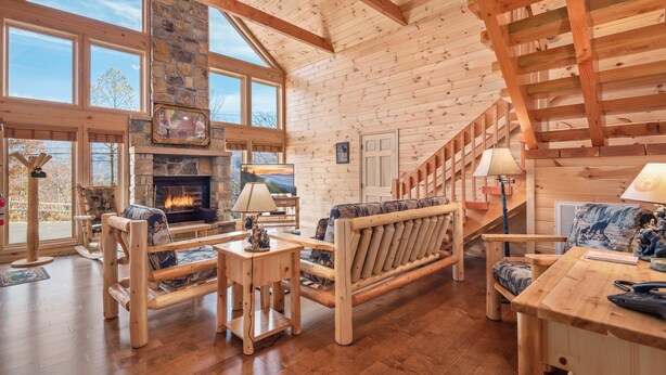 Amplia sala de estar con chimenea, muebles de madera y ventanas grandes.