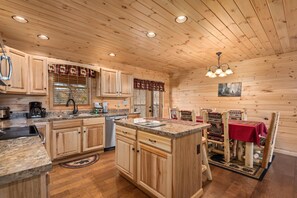 A wooden cabin interior with a kitchen, dining area, and a fireplace. - Key to Heaven (Gatlinburg)