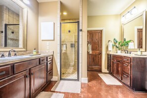 A bathroom with a shower, two sinks, wooden cabinets, and a large mirror. - Spacious 5-bedroom lake front house in Kingsland with game room (Kingsland)