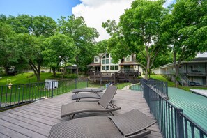 A wooden deck with lounge chairs, a pool, and a building with a deck and stairs. - Spacious 5-bedroom lake front house in Kingsland with game room (Kingsland)