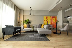 A modern living room with a sectional sofa, a coffee table, and a dining area with a chair. - Apartment in Prime Central Location (Bucharest)