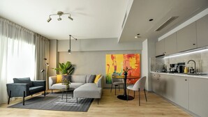 Un salon moderne comprenant un canapé, des fauteuils, une table basse, un lampadaire et un grand tableau abstrait.