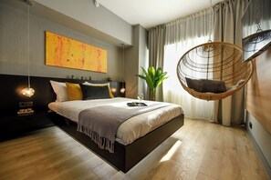 Un dormitorio moderno con una silla colgante, una cama grande y una planta.