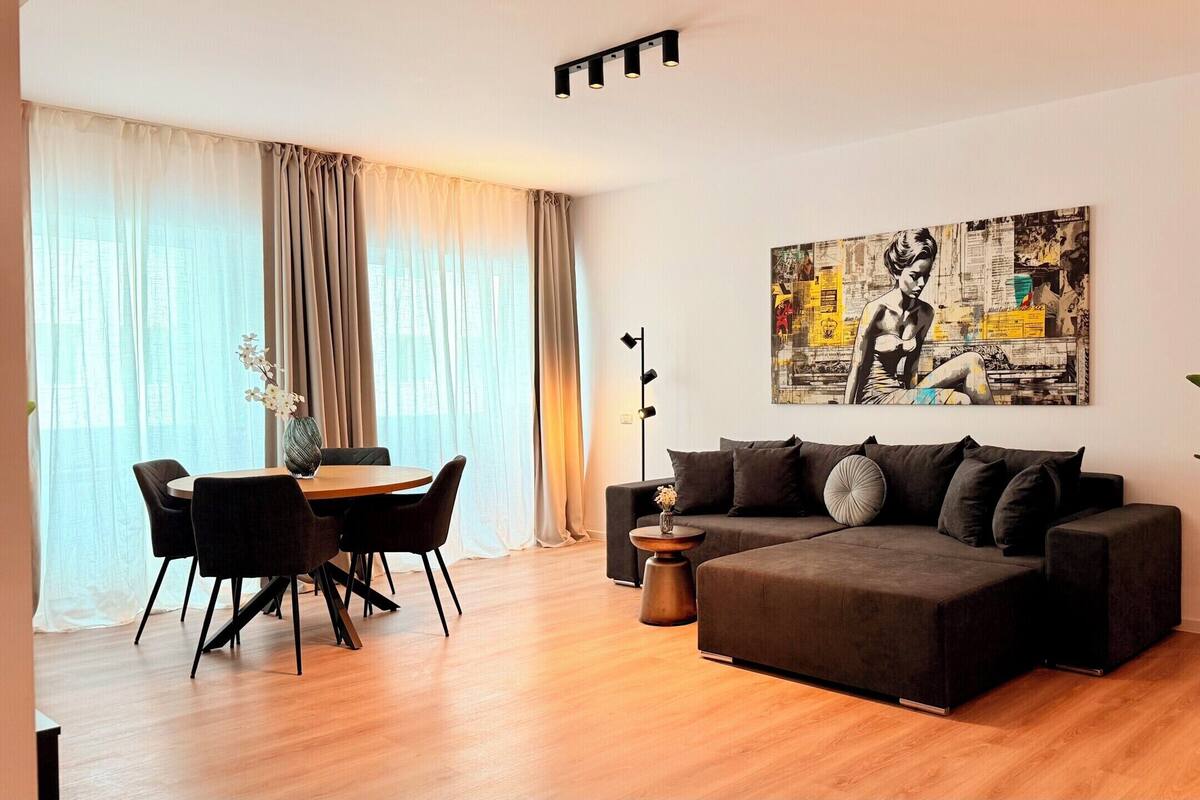 A modern living room with a sofa, dining table, chairs, and a large abstract painting on the wall.