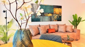 Una sala de estar con un sofá, una mesa de centro, un jarrón con flores y un cuadro en la pared.