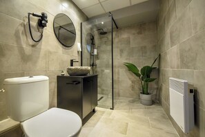 A modern bathroom with a toilet, sink, shower, and a potted plant. - Apartment in Prime Central Location (Bucharest)