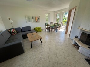 Ein Wohnzimmer mit einer Couch, einem Couchtisch, einem Kamin und einem Essbereich mit Stühlen und Tisch.