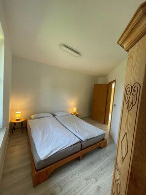 Ein Schlafzimmer mit Bett, Nachttischlampen, einem Kleiderschrank und einer Tür zu einem anderen Raum.