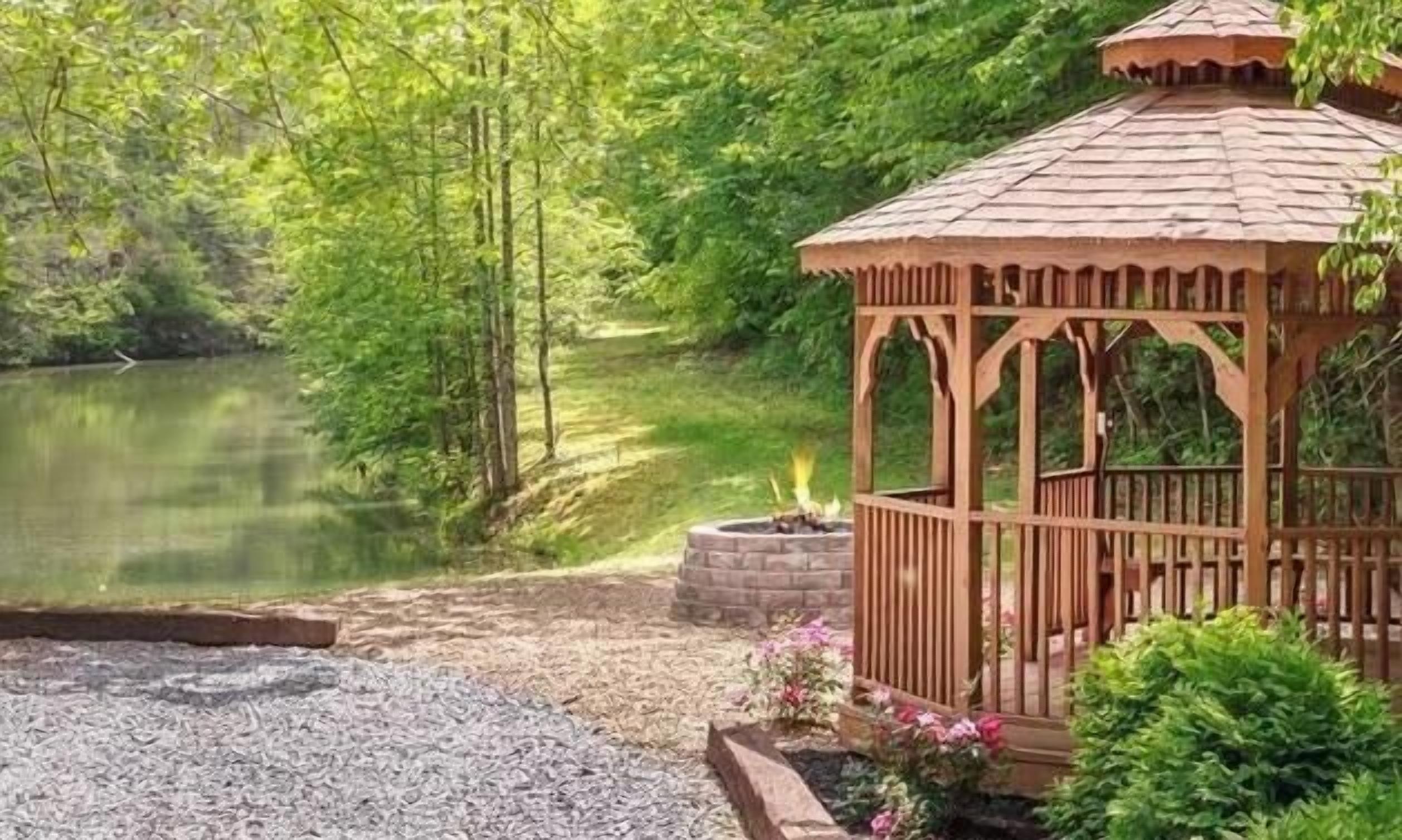 Un gazebo con un braciere in mattoni e uno stagno sullo sfondo.