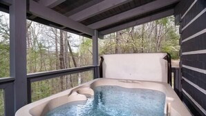 Ein Whirlpool mit einer Holzterrasse und Blick auf Bäume.
