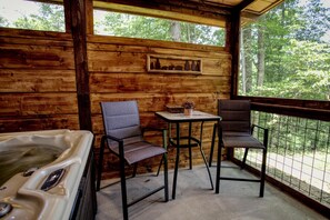 A wooden cabin interior with a hot tub, two chairs, a table, and a framed picture on the wall. - Scenic Solitude (Sevierville)