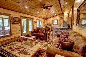 Ein Holzblockhaus mit Wohnzimmer, Küche und Essbereich.