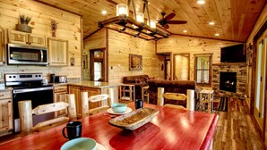 Un interior de madera con cocina, comedor y chimenea.