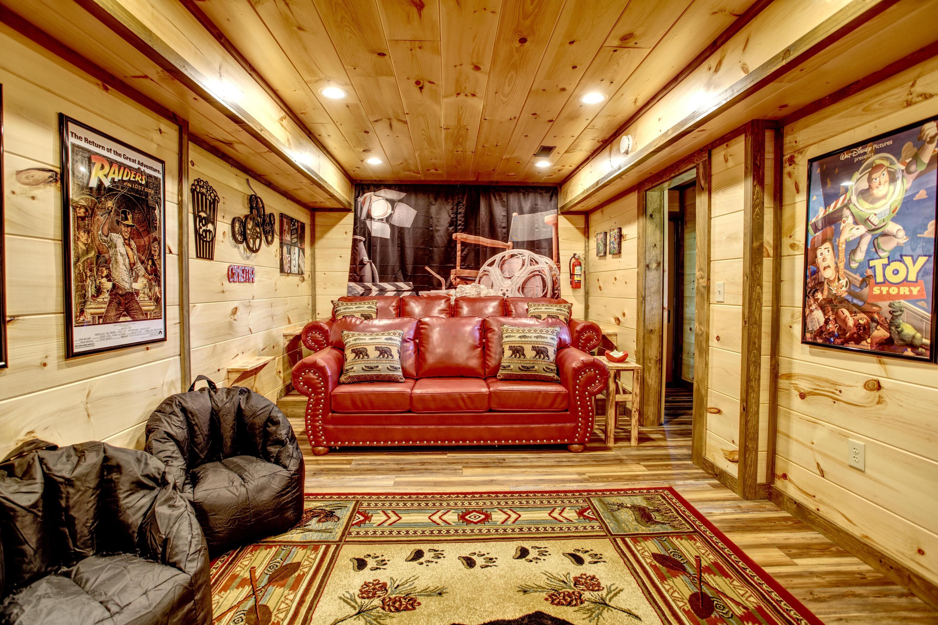A log cabin interior with a red leather sofa, a black bean bag, and a patterned rug.