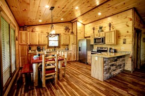 Ein Holzblockhaus-Innenraum mit Küche, Essbereich und einer Steinserviertheke.
