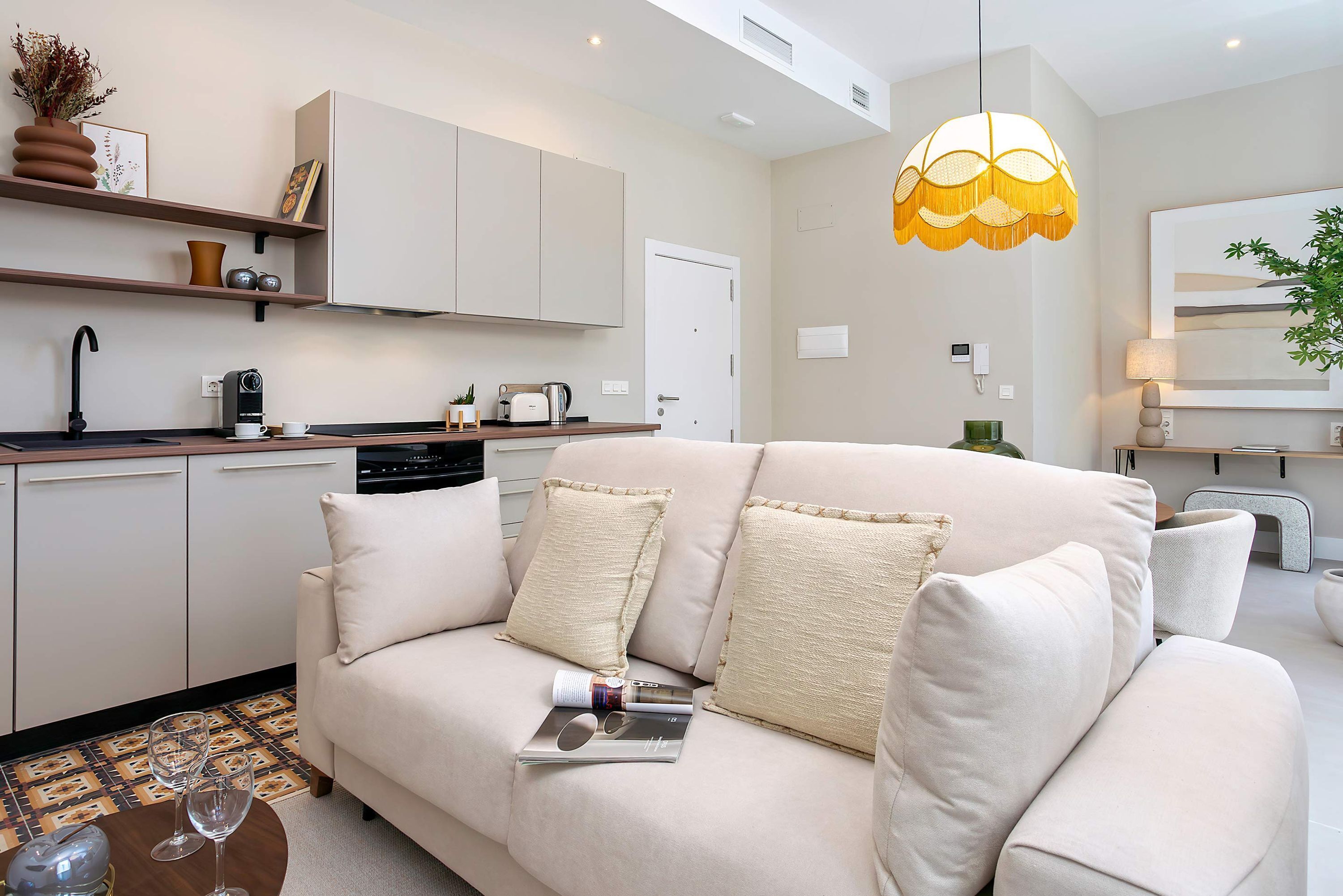 A modern kitchen with white cabinets, a coffee machine, and a hanging light fixture.