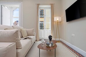 A modern hotel room with a sofa, a coffee table with decorative items, a TV mounted on the wall, and a view through a window. - Charming 1bedroom Apt in Granada San Anton 201 (Granada)