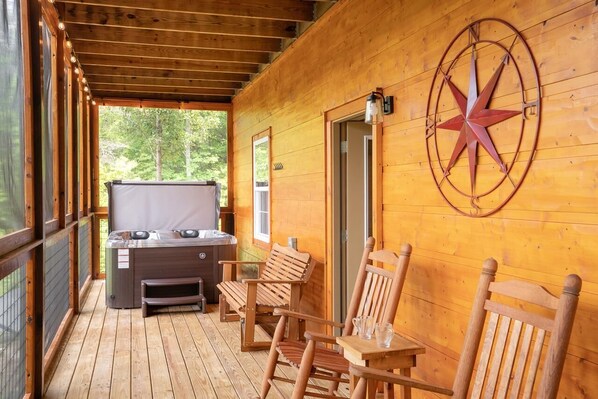 Eine Holzterrasse mit Whirlpool, Holzstühlen und einer Sternencompass an der Wand.