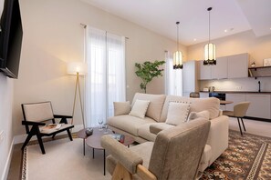 Ein modernes Wohnzimmer mit einer Couch, Sesseln, einem Couchtisch und einem Fernseher.