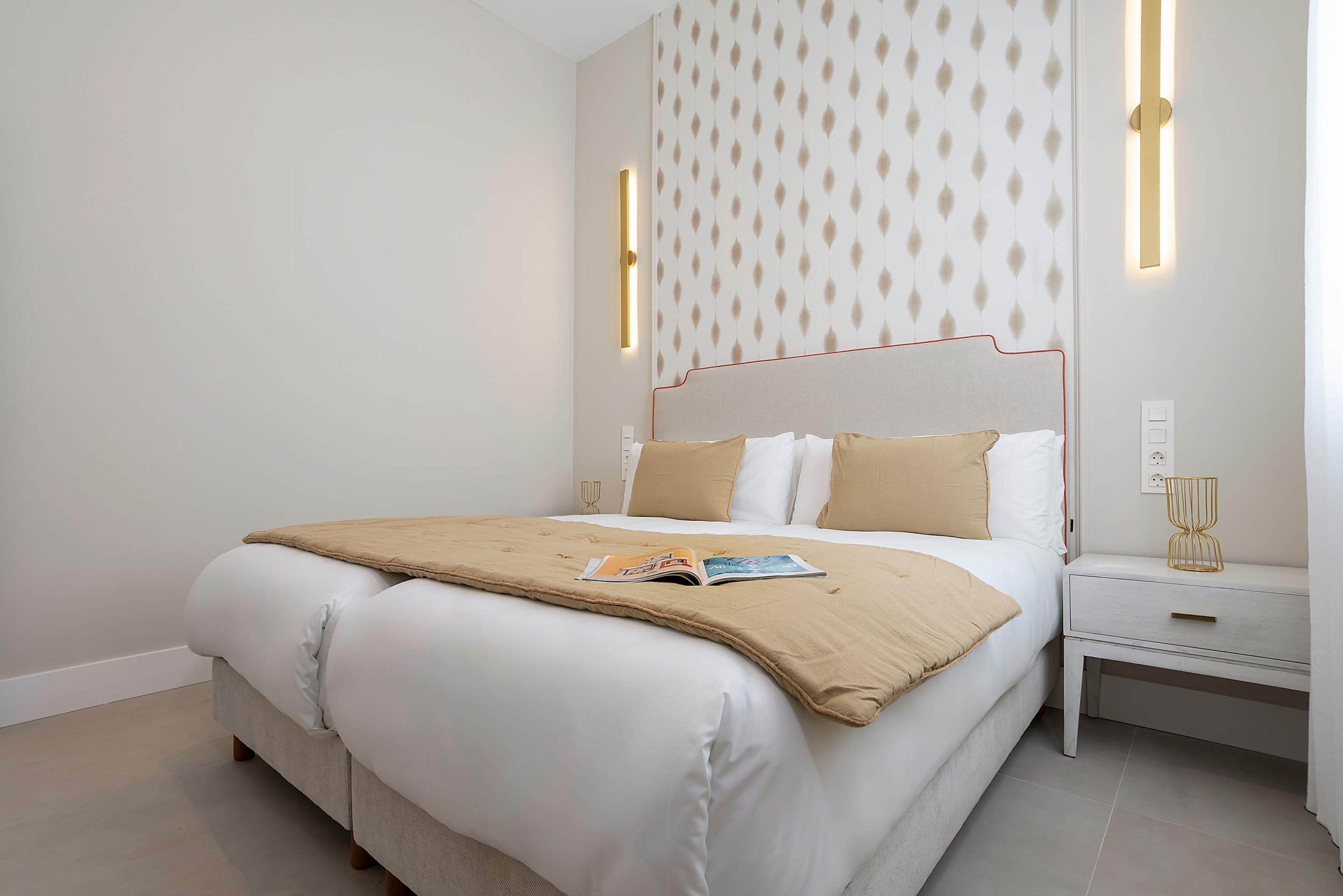 Een moderne slaapkamer met een bed, nachtkastjes en een behang met een patroon.