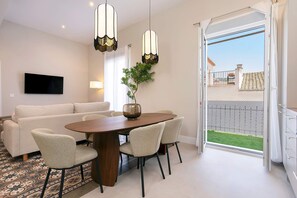 Ein moderner Essbereich mit Holztisch, vier Stühlen, einem Fernseher und einem Balkon mit Blick.