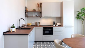 A modern kitchen with white cabinets, a wooden countertop, a built-in oven, and a dining area with a round table and chairs. - Spacious Apartment in Granada Center San Anton 204 (Granada)