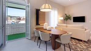 Ein modernes Wohnzimmer mit Essbereich, einer Couch, einem Fernseher und Blick durch eine Glastür.