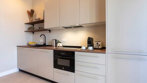 Eine moderne Küche mit weißen Schränken, einem schwarzen Backofen und einem Edelstahl-Wasserkocher.