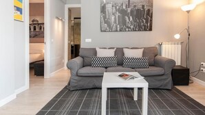 A modern living room with a grey sofa, black and white patterned pillows, a white coffee table, and a cityscape painting on the wall. - Plaza de Castilla II (Madrid)