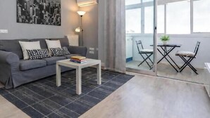 A modern living room with a grey sofa, a white coffee table, and a dining area with two chairs. - Plaza de Castilla II (Madrid)