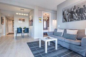 A modern living room with a grey sofa, a white coffee table, and a black and white patterned rug. - Plaza de Castilla II (Madrid)