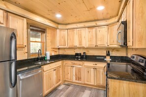 Una cocina moderna con armarios de madera, electrodomésticos de acero inoxidable y una encimera negra.