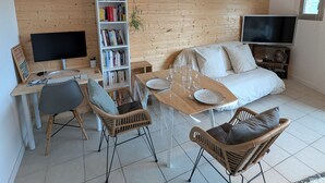 Uma sala de estar moderna com parede de madeira, uma estante, uma TV de tela plana, um sofá, duas poltronas e uma mesa de jantar.