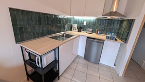 Uma cozinha compacta equipada com lava-louças, micro-ondas, pia e torradeira.