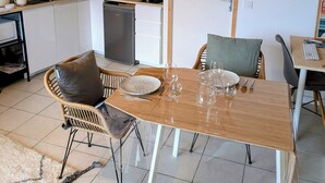 Uma cozinha moderna com área de jantar, incluindo uma mesa posta para dois, uma cafeteira e uma máquina de lavar louça.
