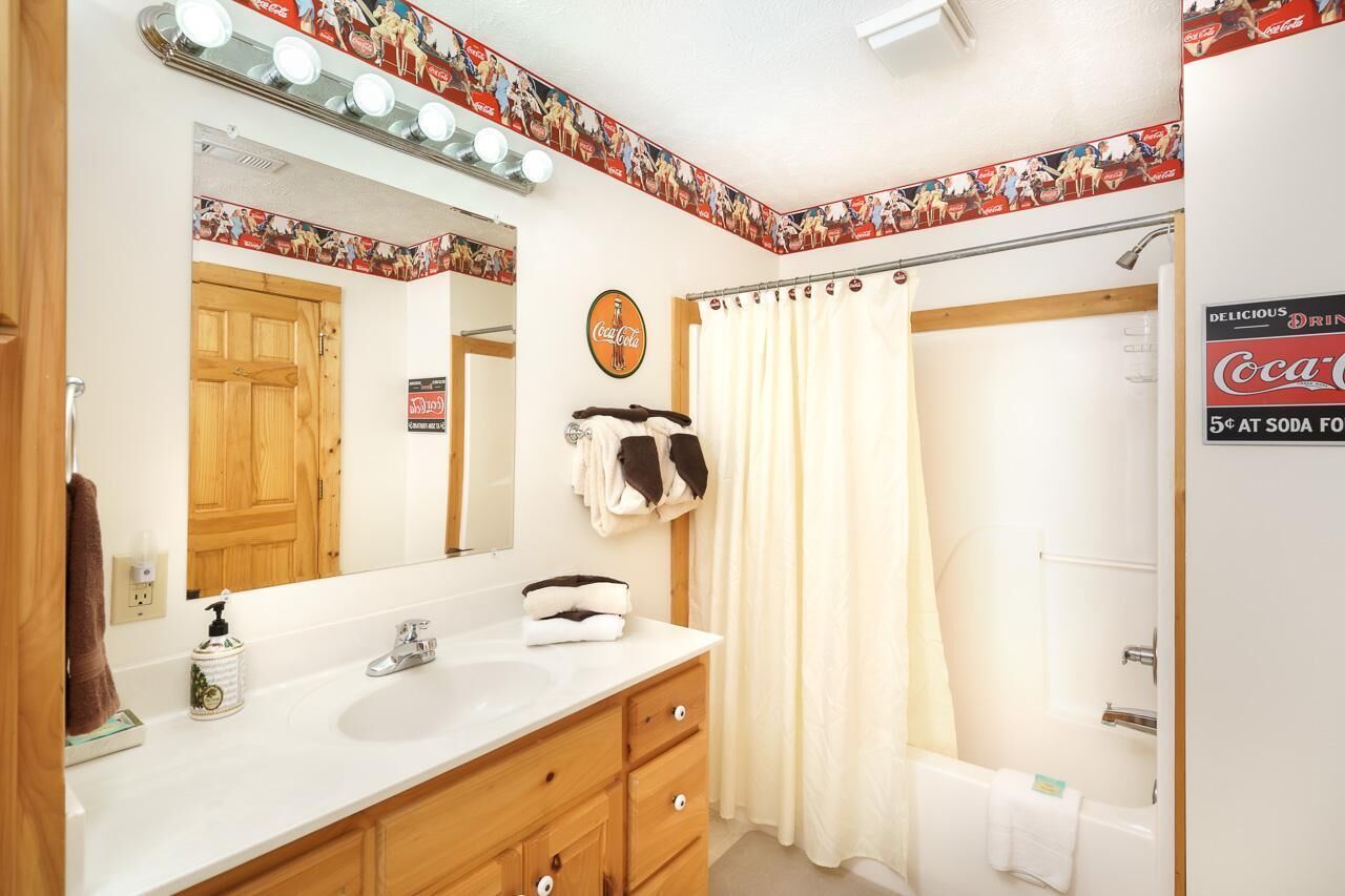 A bathroom with a sink, mirror, and shower curtain.