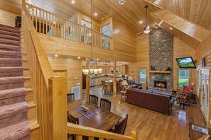 A spacious wooden cabin with a central fireplace, a dining area, and a kitchen. - Cork's Creekside (Cosby)