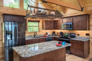 A modern kitchen with granite countertops, stainless steel appliances, and wooden cabinetry. - Four Bears (Gatlinburg)