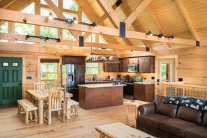 Eine geräumige Holzhütte mit einer großen Küche, einem Essbereich und einem gemütlichen Wohnzimmer.