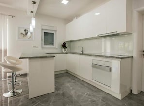 A modern kitchen with white cabinetry, a granite countertop, a built-in dishwasher, and a pendant light. - Villa Antonija With Outdoor Pool (Imotski)