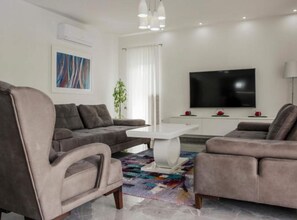 A modern living room with a grey sofa, a white coffee table, a flat-screen TV, and a colorful rug. - Villa Antonija With Outdoor Pool (Imotski)