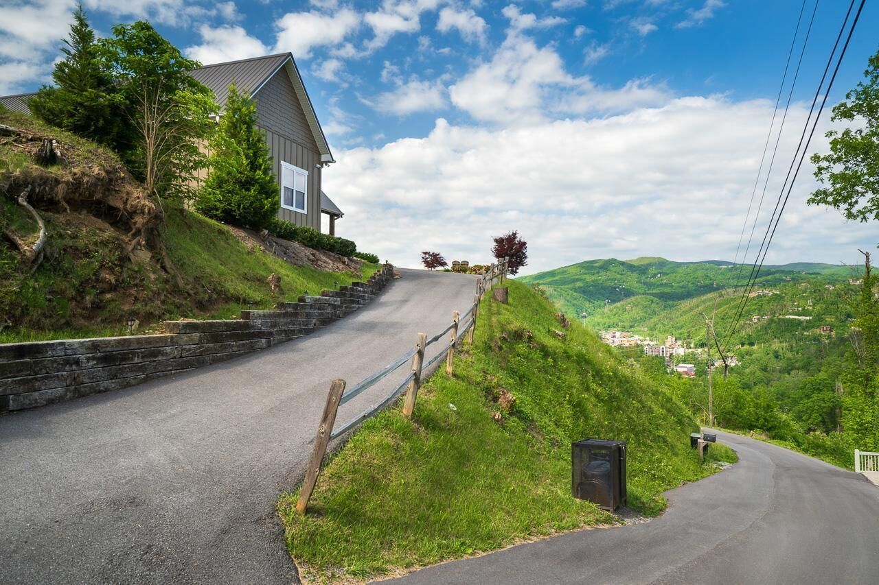 A winding road with a house on a hillside, surrounded by greenery and hills.