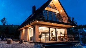 A modern house with a large glass front, a balcony, and a wooden exterior.