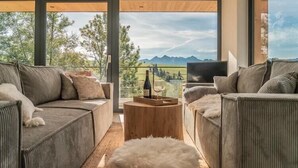 A modern living room with a large window, a sofa set, a coffee table, and a television.