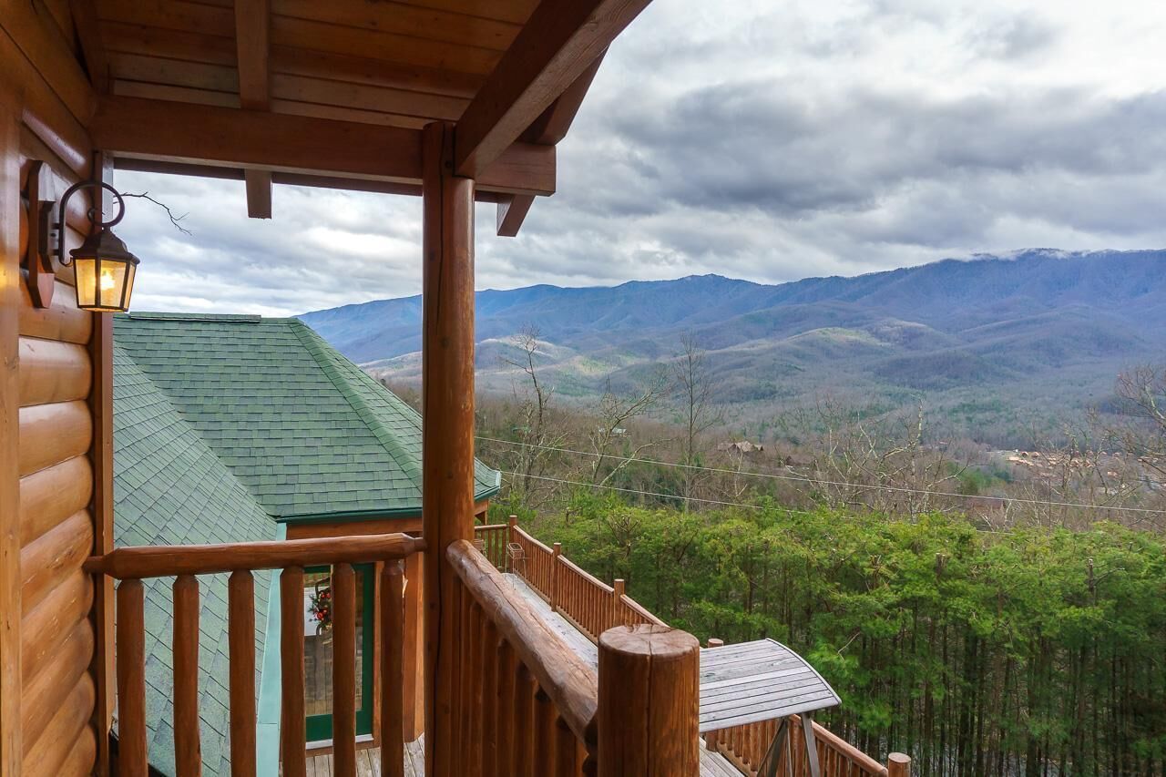 Una cabaña de madera con balcón que da a un paisaje montañoso.