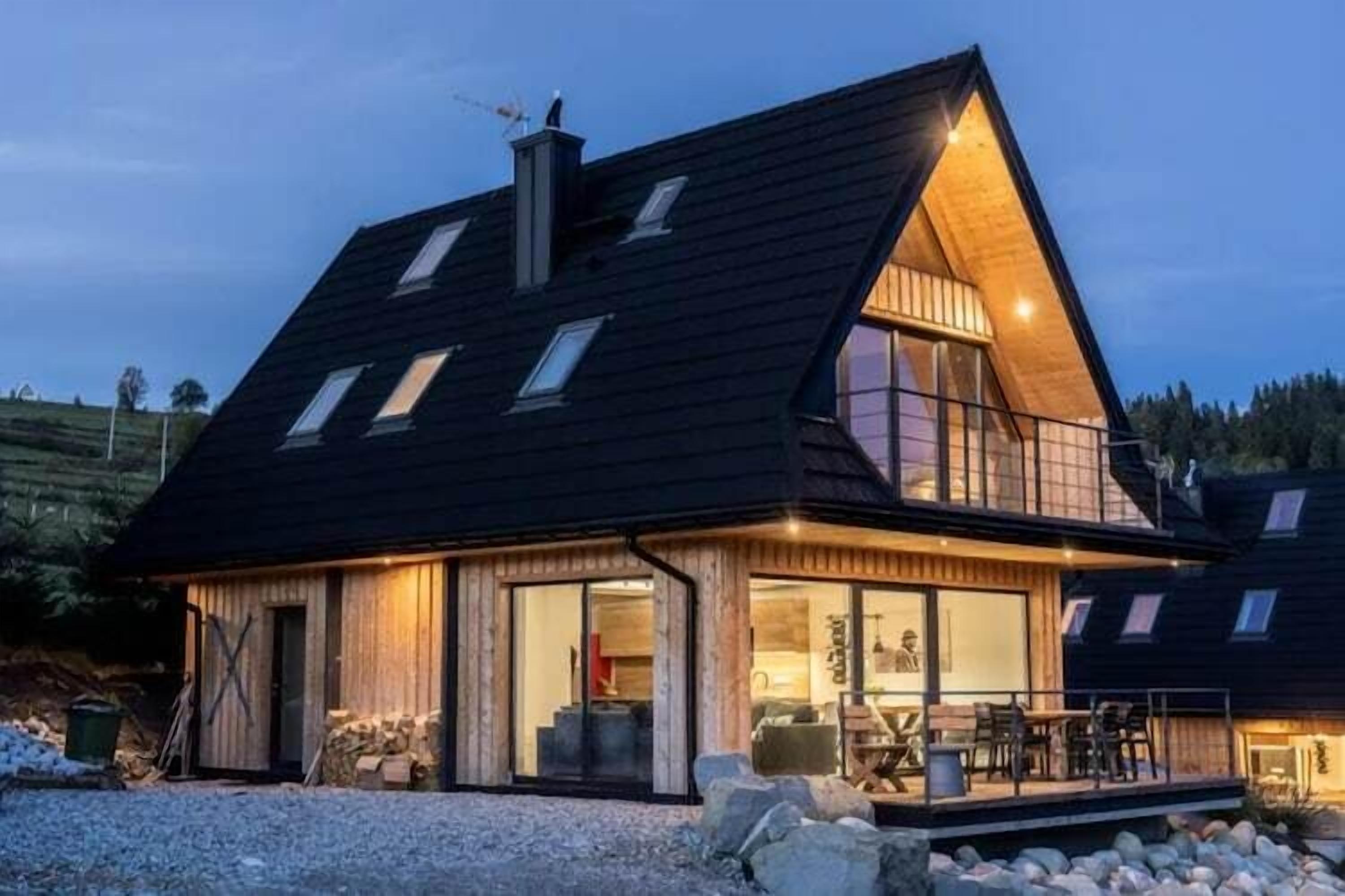 Une maison moderne avec un toit en pente, de grandes fenêtres et un balcon.