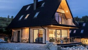 Et moderne hus med skråt tag, store vinduer og en balkon.